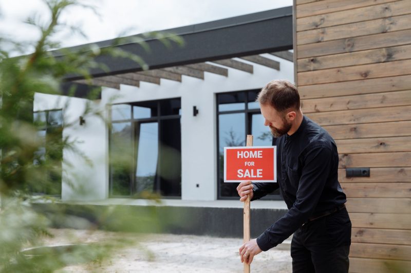 Home 9 Man placing a home for sale sign outside a modern house for 1785862952